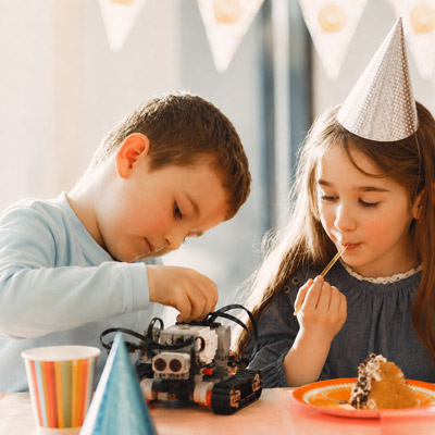 Zwei Kinder bei einem Lego Robotik Workshop an einem Geburtstagstisch