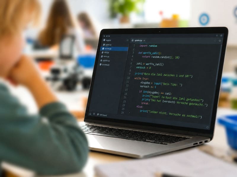 Bub, ca. 10 Jahre befindet sich in einem Vor-Ort-Kurs für Programmieren und ist vertieft in den Code am Bildschirm