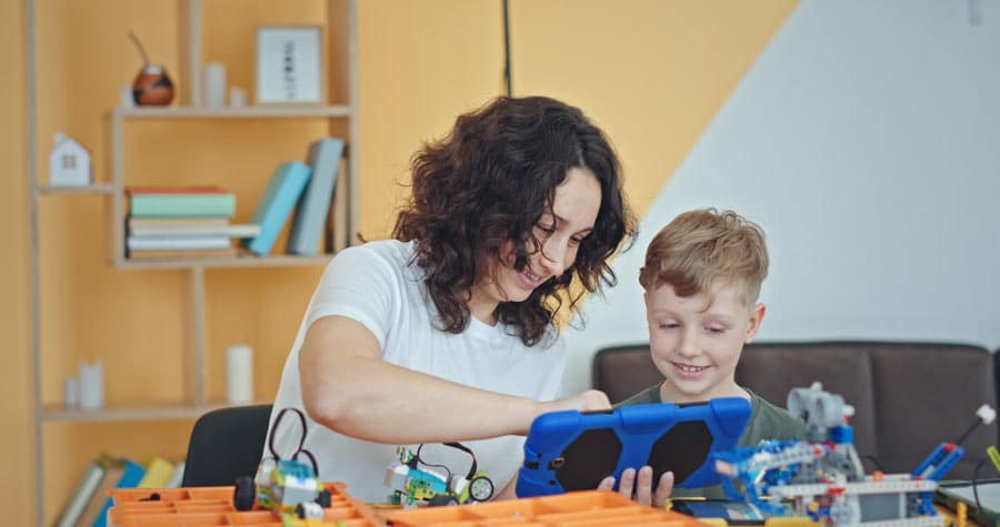 Mutter und Sohn beim Family Day, wie sie mit einem Tablet einen kleinen fahrbaren LEGO-Roboter programmieren